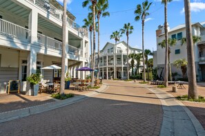 A hotel with multiple balconies, outdoor seating, and palm trees.