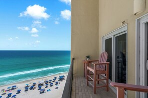 Ein Balkon mit Blick auf den Strand, ein Holzstuhl und eine Tür mit der Nummer 725.