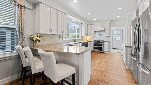 A modern kitchen with white cabinets, a granite countertop, and stainless steel appliances. - Elegant Family Haven (Monaca)
