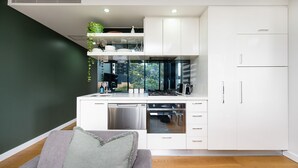 A modern kitchen with white cabinetry, a dishwasher, a stove, and a coffee maker.