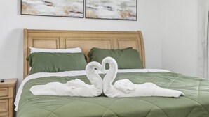 A bed with a green quilted bedspread and two pillows, one green and one white. - Welcome to The Chelsea Inn! This cozy, modern 3BR/2BA home is designed for all! (Tampa)