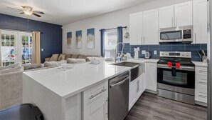 A modern kitchen with white cabinets, a built-in microwave, and a red bow on the oven. - Welcome to The Chelsea Inn! This cozy, modern 3BR/2BA home is designed for all! (Tampa)