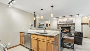 Una cocina moderna con una isla central, lavavajillas integrado y una chimenea de piedra.