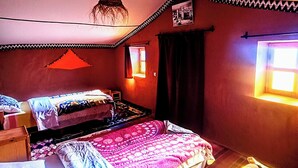 A room with two beds, a hanging light fixture, a patterned rug, and a window with curtains. - Charming Berber camp in Mhamid Desert  (Zagora)