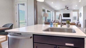 Una cocina moderna con lavavajillas integrado, un lavabo y una zona de comedor con una silla y una mesa.