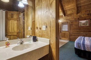 A wooden cabin-style bathroom with a large mirror, sink, and towel rack. - Tranquility - Hot-Tub, Fireplace (Pigeon Forge)
