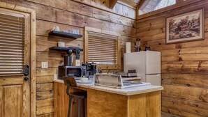 A compact kitchen with wooden walls, a microwave, a coffee maker, and a refrigerator. - Tranquility - Hot-Tub, Fireplace (Pigeon Forge)