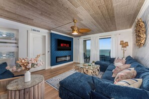 Un salon moderne avec un canapé bleu, une table basse en verre et une cheminée.