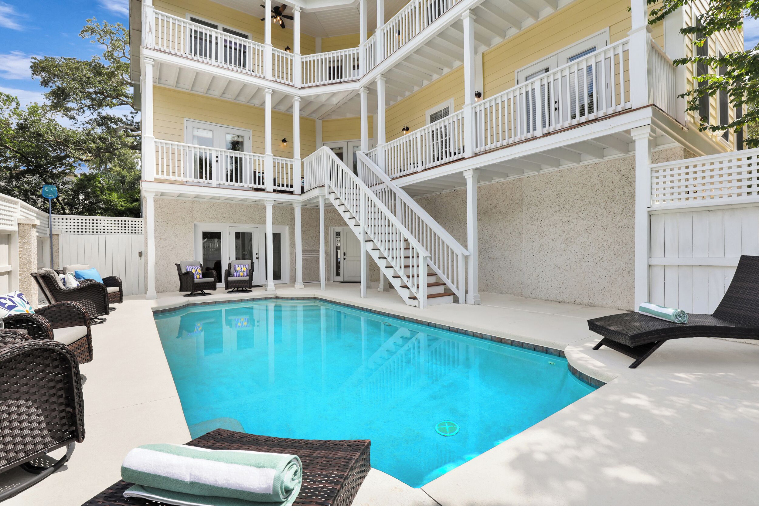 A multi-level outdoor pool area with a staircase, lounge chairs, and a covered seating area.