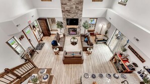 A spacious living area with a fireplace, multiple seating options, and a kitchen area with a granite countertop. - Creekside Cabin / Branson, SDC, Lakes, In/Out Pool (Hollister)