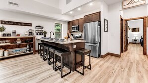 A modern kitchen with a central island, stainless steel appliances, and a wooden floor. - Creekside Cabin / Branson, SDC, Lakes, In/Out Pool (Hollister)