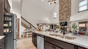A spacious kitchen with granite countertops, a stone accent wall, and a modern design. - Creekside Cabin / Branson, SDC, Lakes, In/Out Pool (Hollister)