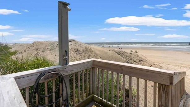 A wooden deck overlooking a sandy beach with a clear sky.