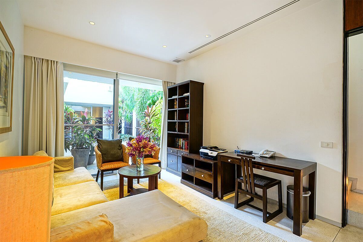 A modern living room with a sofa, a coffee table, a bookshelf, and a desk with a printer.