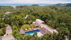 A resort with a swimming pool, thatched-roof buildings, and lush greenery. - Villa Samakee (Choeng Thale)