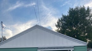 A single-story building with a green exterior and a white door. - Goodturn Cottage (Cody)