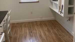 A room with a window, wooden flooring, a white desk, and a built-in shelving unit. - Goodturn Cottage (Cody)