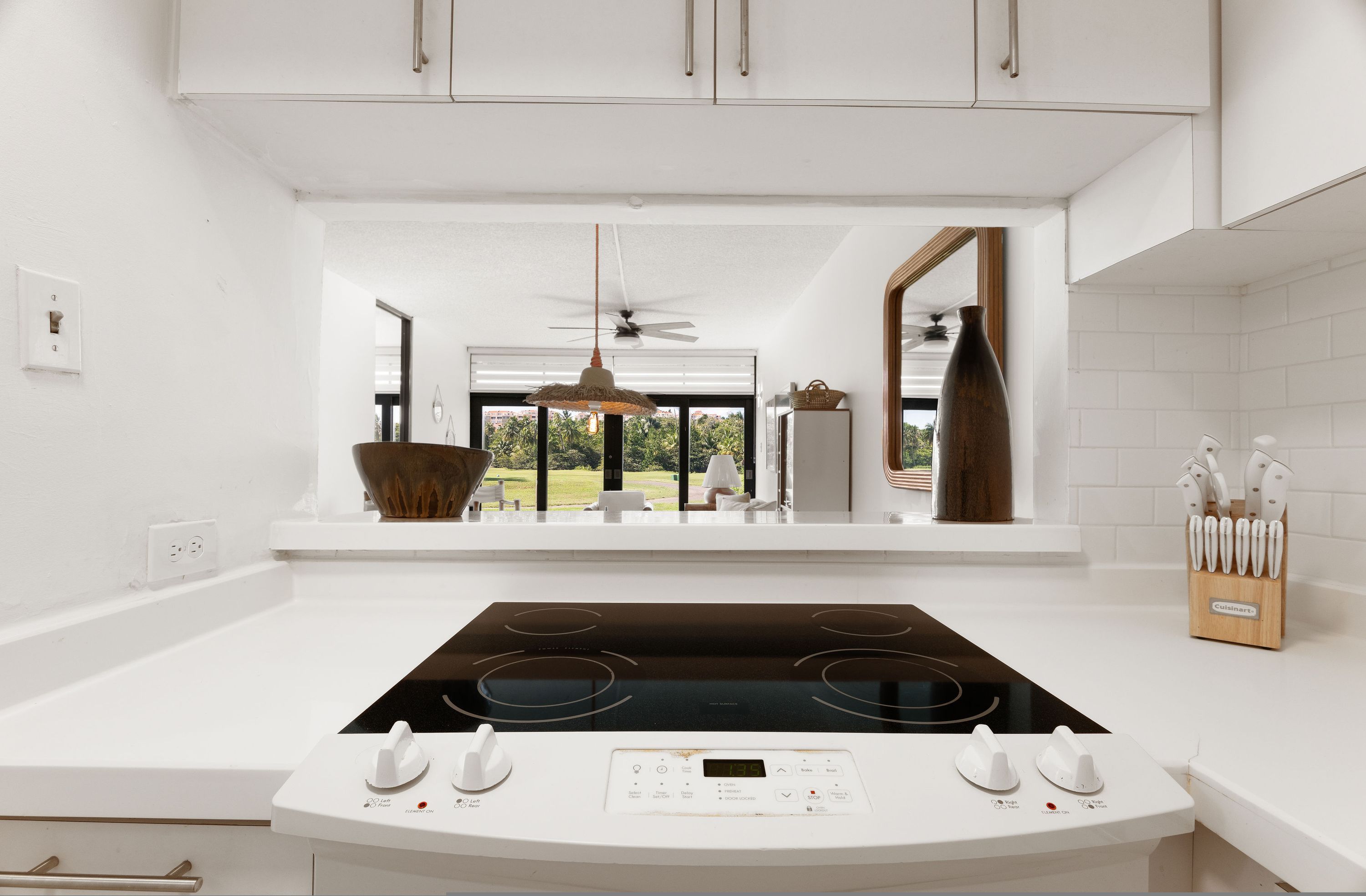 Una cocina moderna con una isla central, armarios blancos y vistas al exterior.