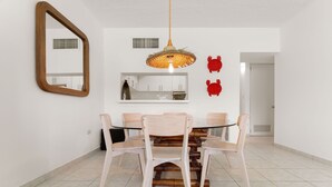 A dining area with a round table, four chairs, a hanging light fixture, and a mirror on the wall.