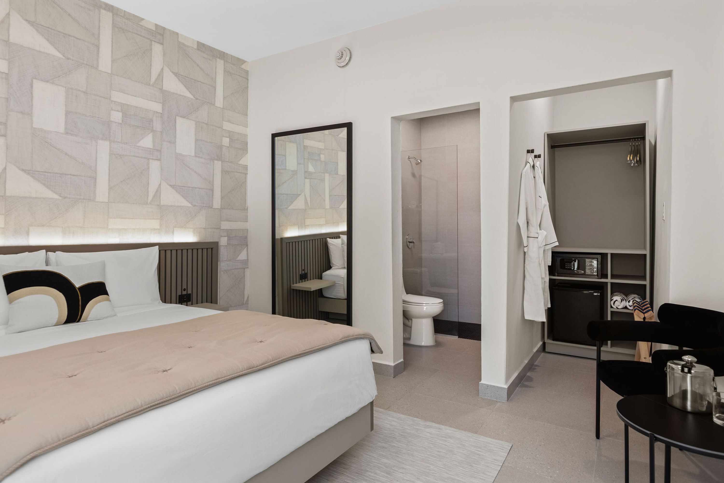 Une chambre d’hôtel moderne dotée d’un grand lit, d’une douche, de toilettes, d’une petite kitchenette et d’un coin salon.