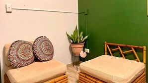 A room with two beige sofas, a green wall, a potted plant, and a sign indicating free Wi-Fi.