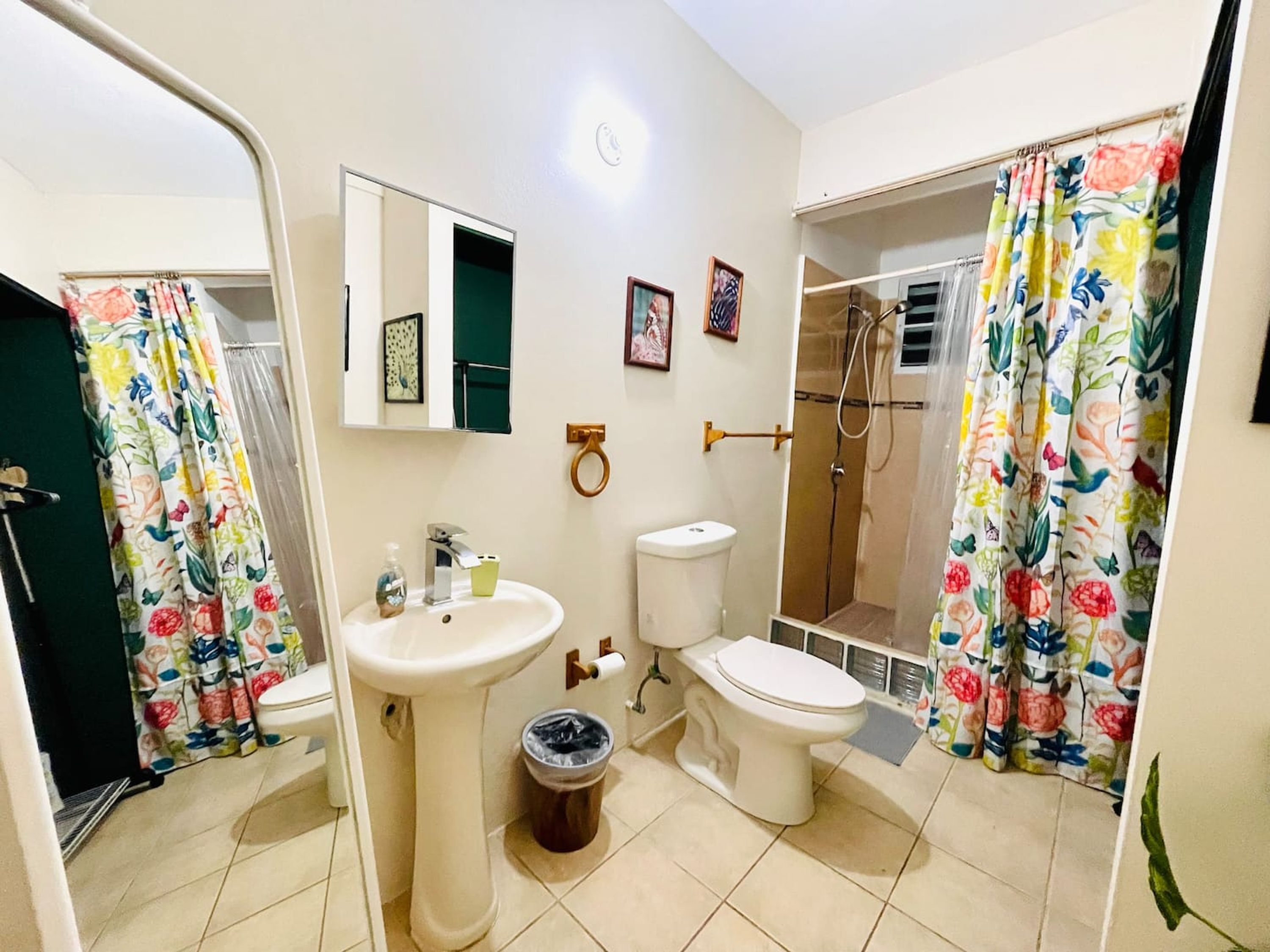 A bathroom with a sink, toilet, shower, and a mirror.