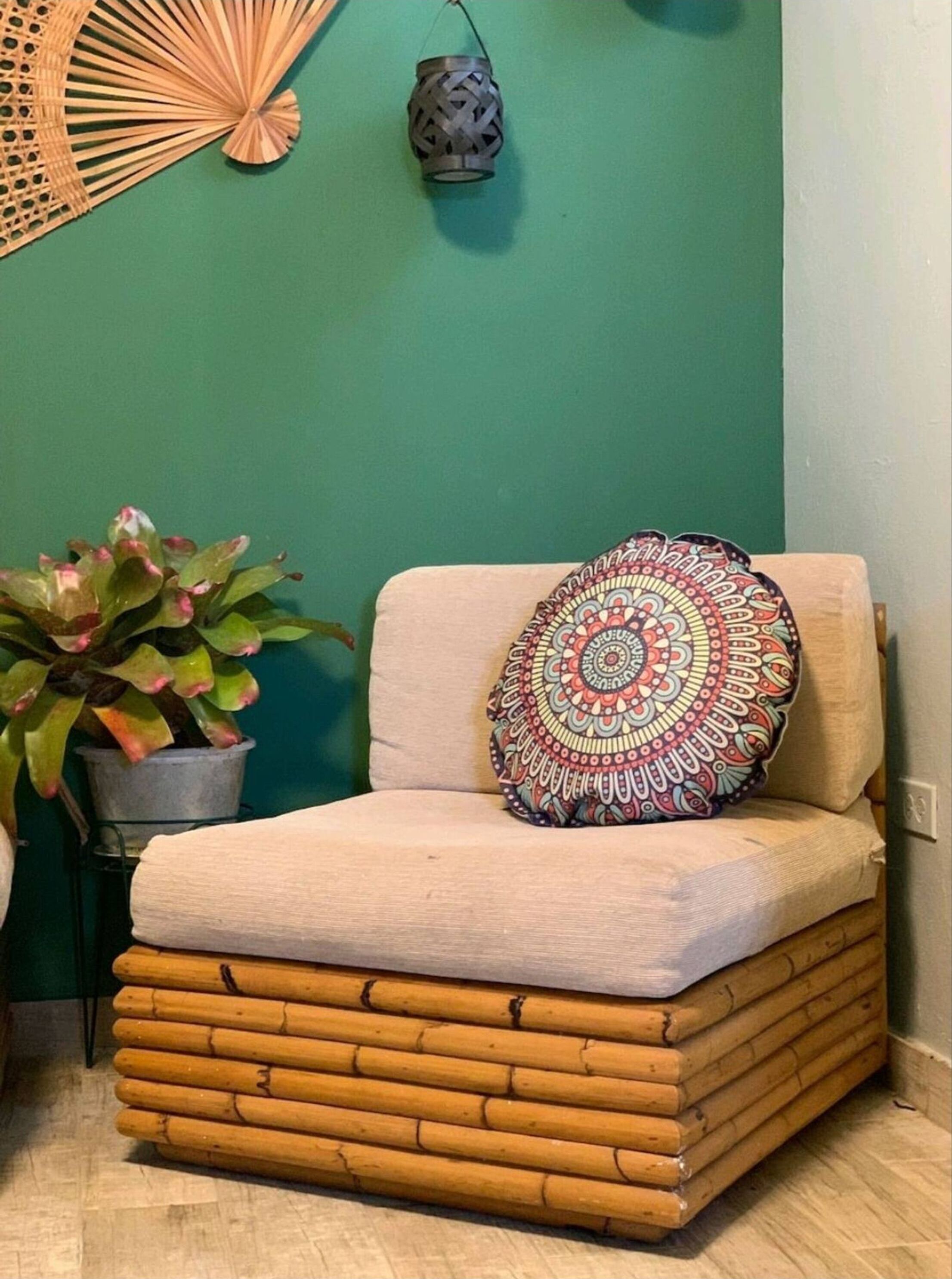 A corner seating area with a cushioned bench, a decorative pillow, a potted plant, and two wall-mounted lanterns.