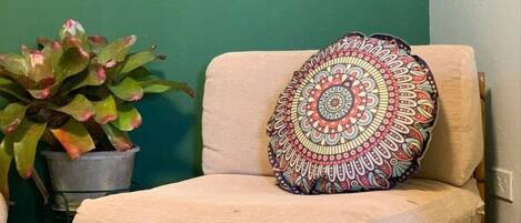 A corner seating area with a cushioned bench, a decorative pillow, a potted plant, and two wall-mounted lanterns.