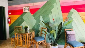 A room with a colorful wall, a round table with chairs, and a potted plant.