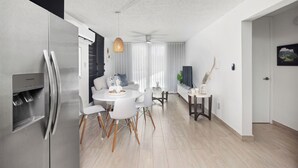 Een moderne keuken met een inbouwkoelkast, een eethoek met een ronde tafel en stoelen, en een plafondventilator.