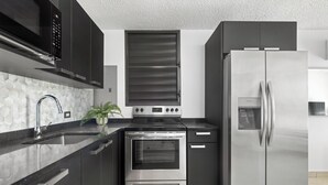 Een moderne keuken met roestvrijstalen apparatuur, zwarte kastjes en een achterwand betegeld met hexagontegels.