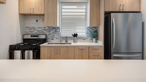 A modern kitchen with wooden cabinets, a stainless steel refrigerator, a gas stove, and a tiled backsplash. - In Condado Beach Beautiful Pool With Tanning Bed (San Juan)