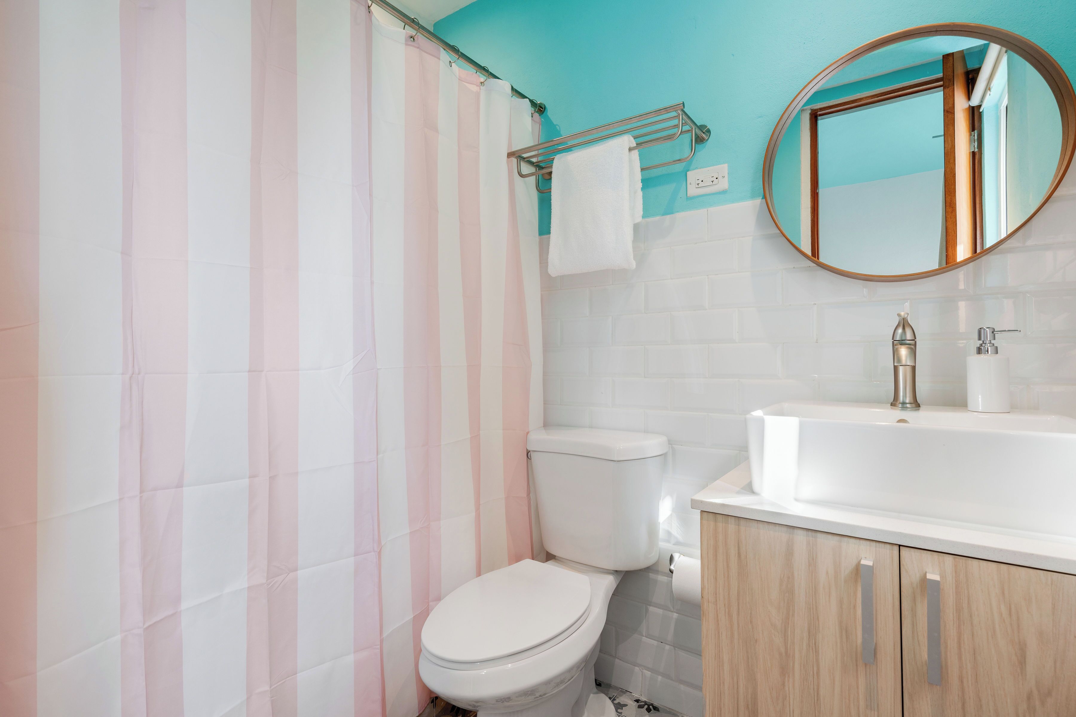 A bathroom with a toilet, sink, and mirror.