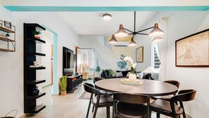 A modern dining area with a round table, black chairs, and pendant lighting. - In Condado Beach Beautiful Pool With Tanning Bed (San Juan)
