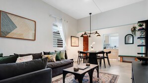 A modern living room with a dark sofa, a coffee table, and a dining area with chairs and a table. - In Condado Beach Beautiful Pool With Tanning Bed (San Juan)