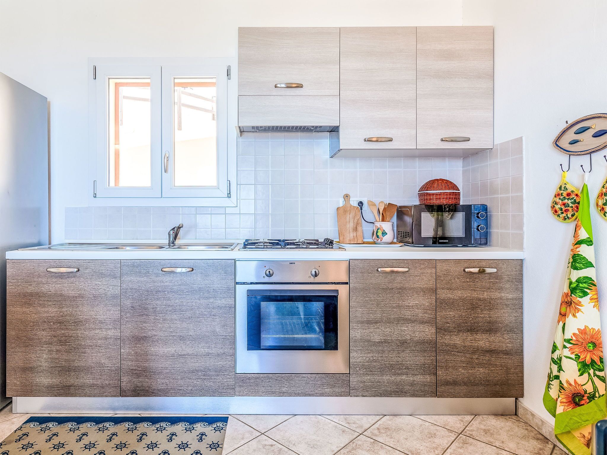 Una cocina moderna con horno empotrado, microondas y cocina a gas.