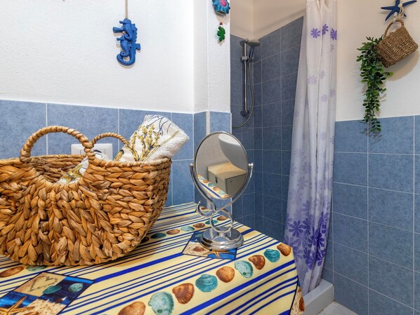Un baño con una cesta tejida, un espejo redondo y una zona de ducha.