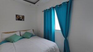 Une chambre à coucher avec un lit, des rideaux de couleur turquoise et un tableau accroché au mur.