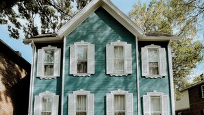 A two-story house with six windows, each with white shutters, and a brick foundation. - Group-Friendly 4BR / 3.5BA / 2 Kitchens + Private Homes Side-by-Side  Sleeps 10 (Dayton)