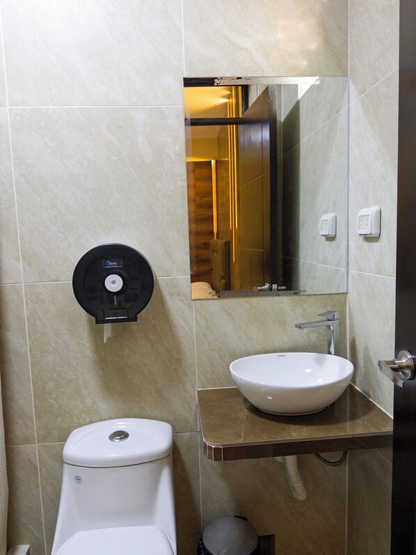Un baño con inodoro, lavamanos y secamanos.