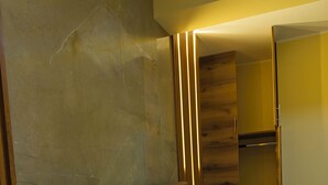 Ett hotellrum med en modern säng, en garderob i trä och en vägg beklädd med marmor.