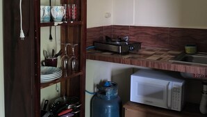 Eine Küche mit einem Holzkasten, einem Gasherd, einer Mikrowelle und einem Wasserspender.