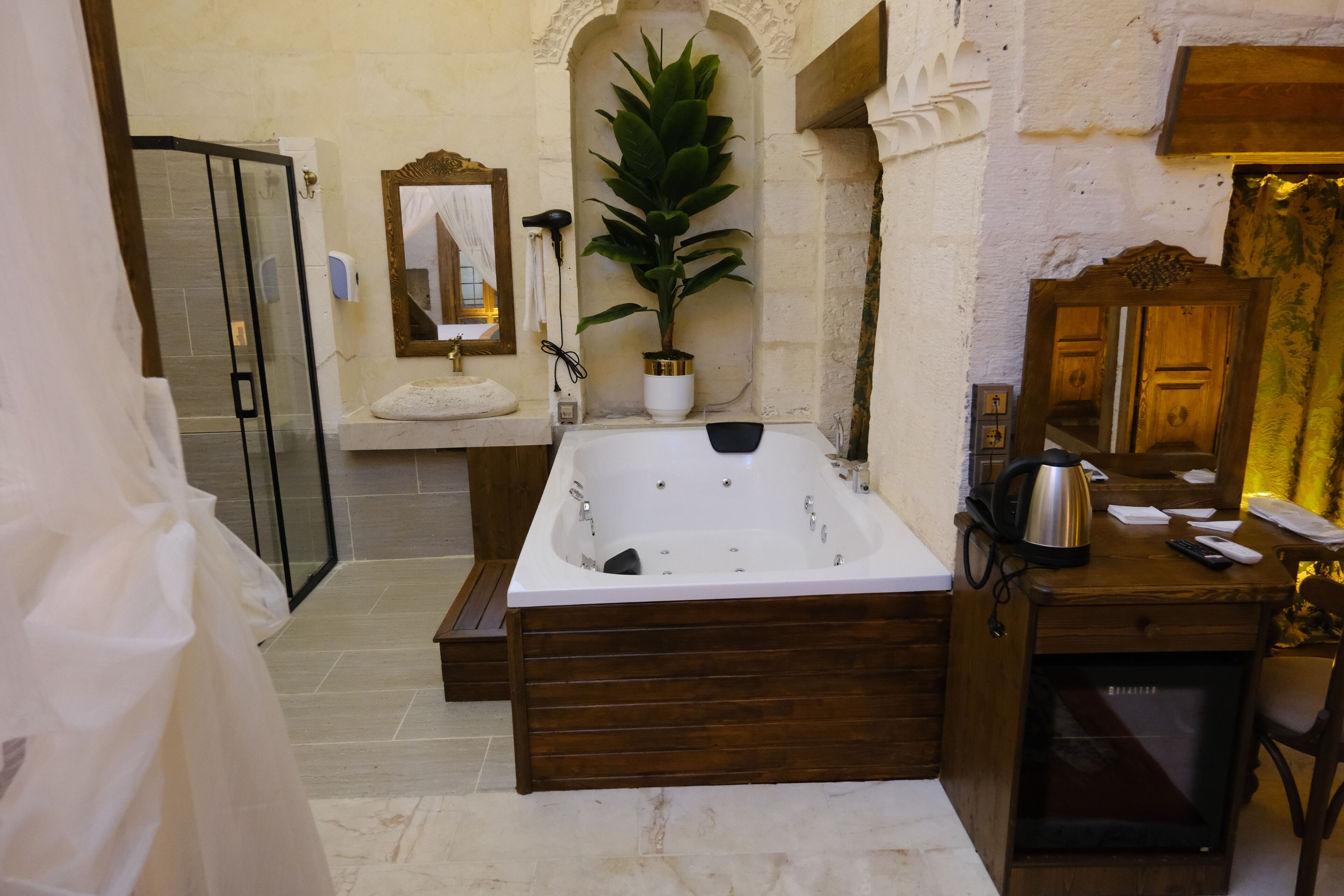 Un baño con una bañera grande, cabina de ducha con mampara de vidrio, lavamanos con toalla y un espejo.