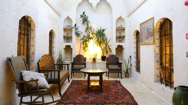 Un intérieur chaleureux avec un coin salon comprenant une table ronde, des chaises et un tapis à motifs.