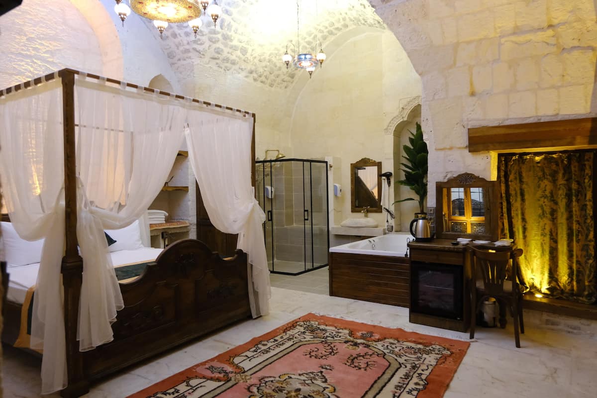 A four-poster bed with a canopy, a shower enclosure, a bathtub, and a fireplace.
