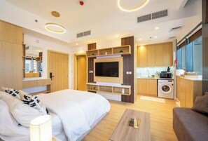 Une chambre d’hôtel moderne équipée d’un grand lit, d’une télévision, d’un coin cuisine et d’un lave-linge.