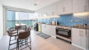 Una cocina moderna con armarios blancos, un salpicadero azul y un amplio ventanal con vistas a la ciudad.