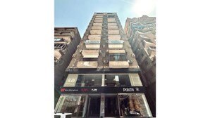 Um edifício de vários andares com diversas lojas no andar térreo, incluindo uma loja visível chamada 