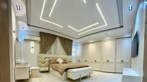 Quarto moderno com uma cama grande, mesas de cabeceira, um banco e um guarda-roupa.