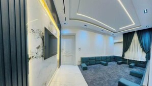Uma sala de estar moderna com piso de mármore, um sofá seccional e uma TV de tela plana na parede.